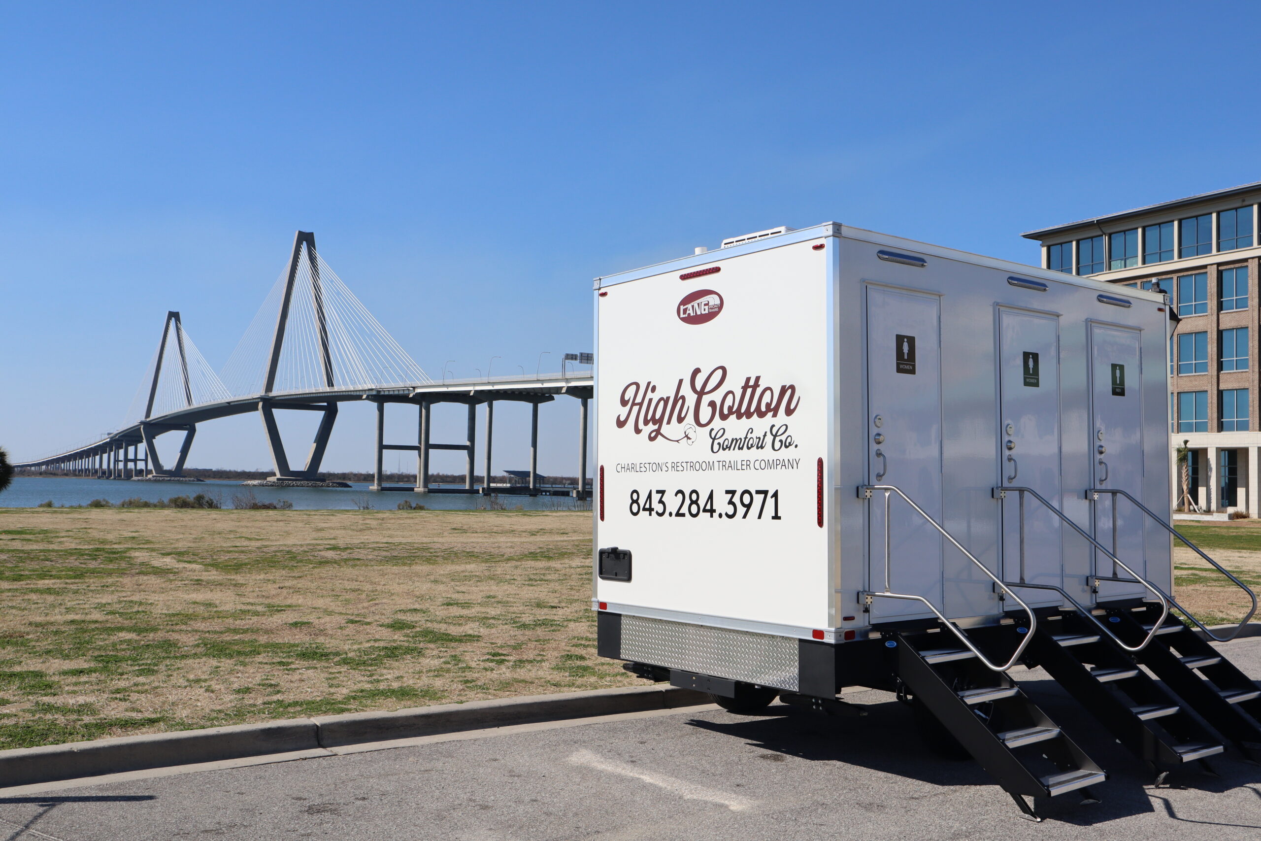 High Cotton Comfort Co luxury restroom trailer parked with the Ravenel Bridge in Charleston, South Carolina in the background.