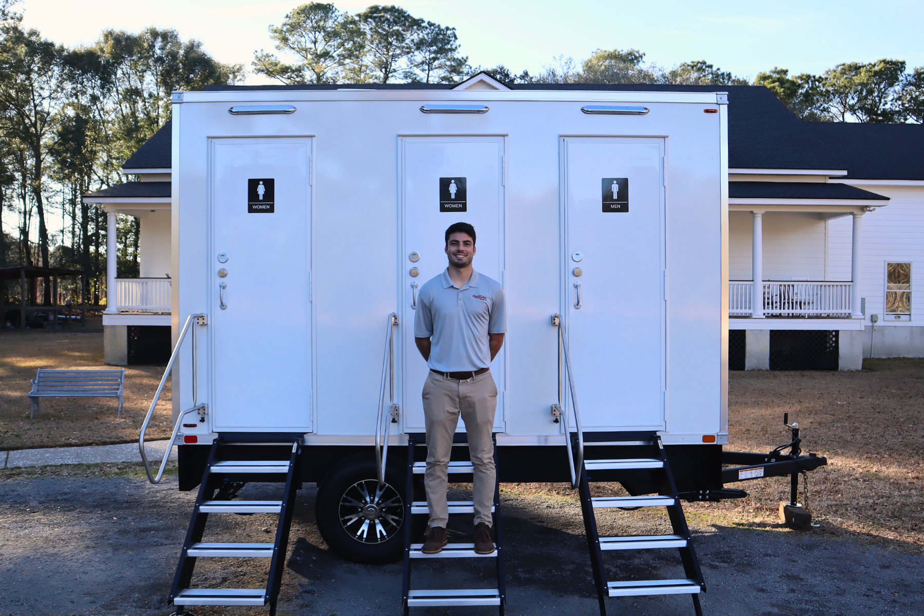 Charleston restroom trailer blog header showing a team member standing in front of a luxury restroom trailer with multiple stalls, highlighting professional rental services and expertise.